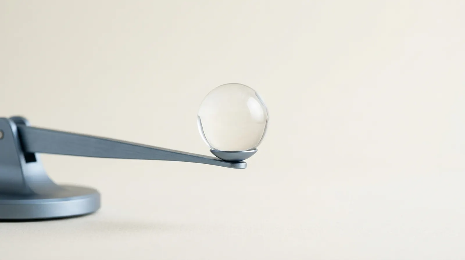 A glass sphere balanced on a minimalist steel-blue scale arm